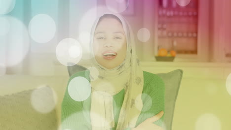 animation of light spots over biracial woman in hijab smiling