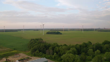 Drone-aerial-view-of-many-windmills-spinning-at-dusk-in-open-fields