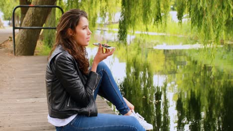 mujer hablando por teléfono móvil cerca del río 4k