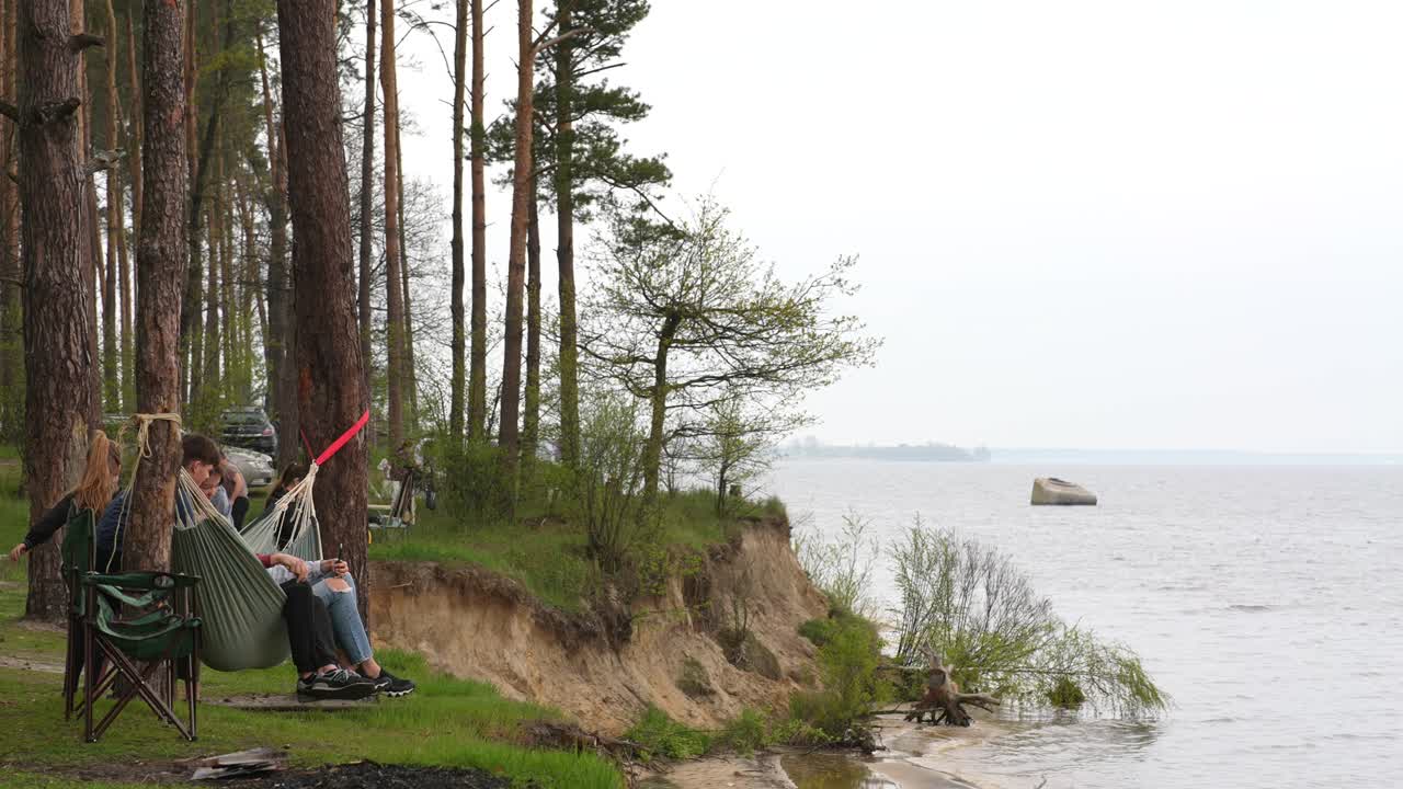People relaxing in hammocks near a river in a forest