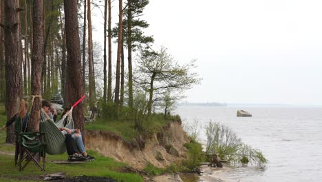 people relaxing in hammocks near a river in a forest