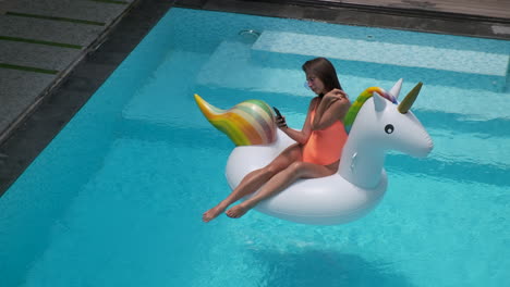 Woman relaxing in a pool with an inflatable unicorn