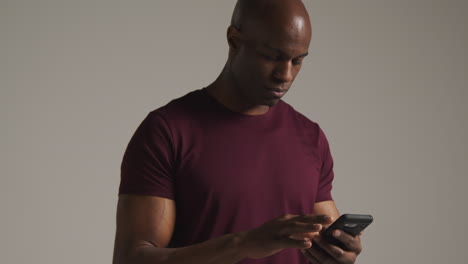 studio shot of excited mature man with mobile phone celebrating winning money against grey background