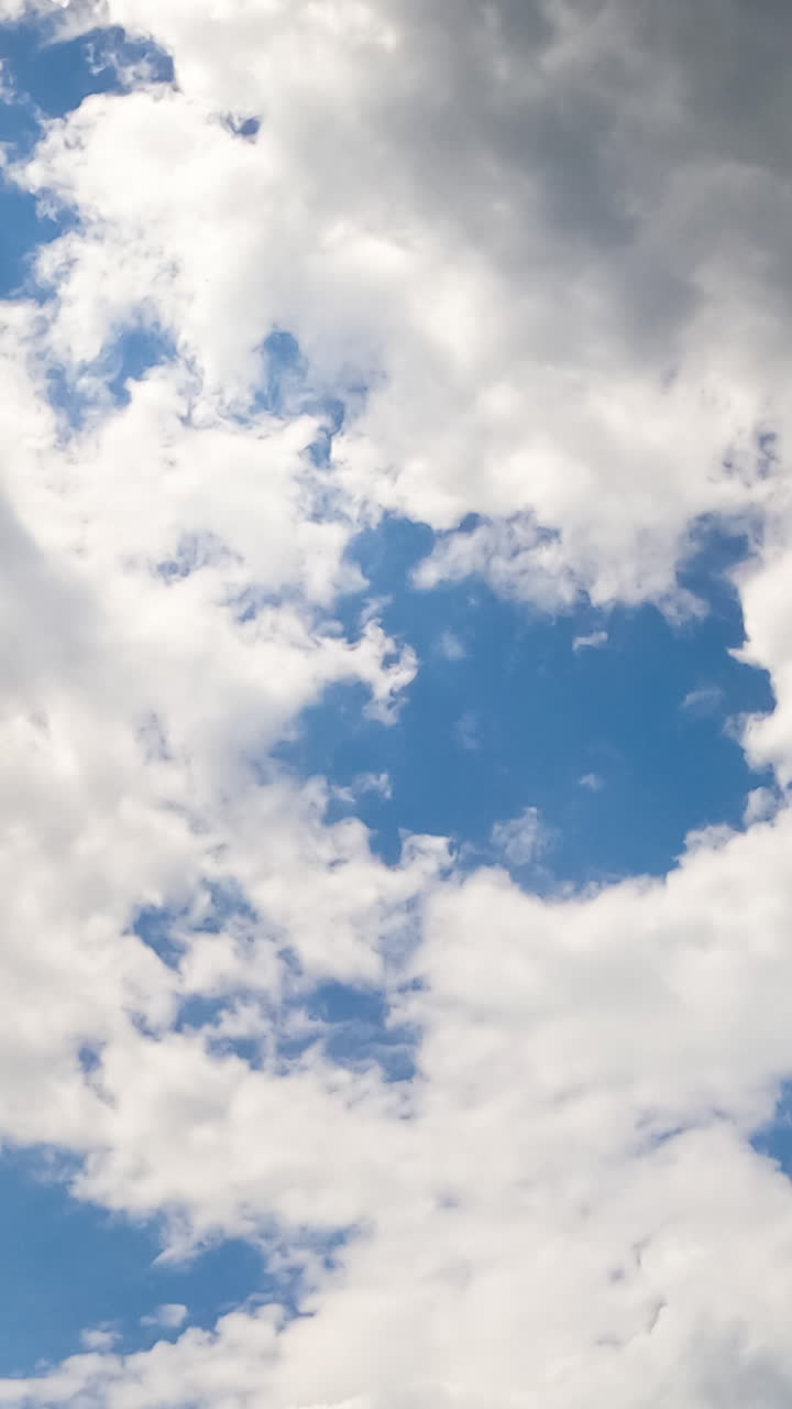 Fluffy white and grey clouds in the atmosphere. Formation of the cloudscape from low angle view. Timelapse. Vertical video