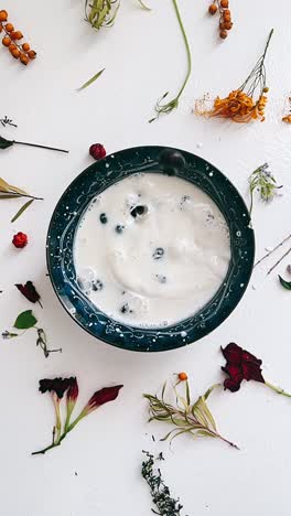 milk and blueberries in a bowl with floral arrangement