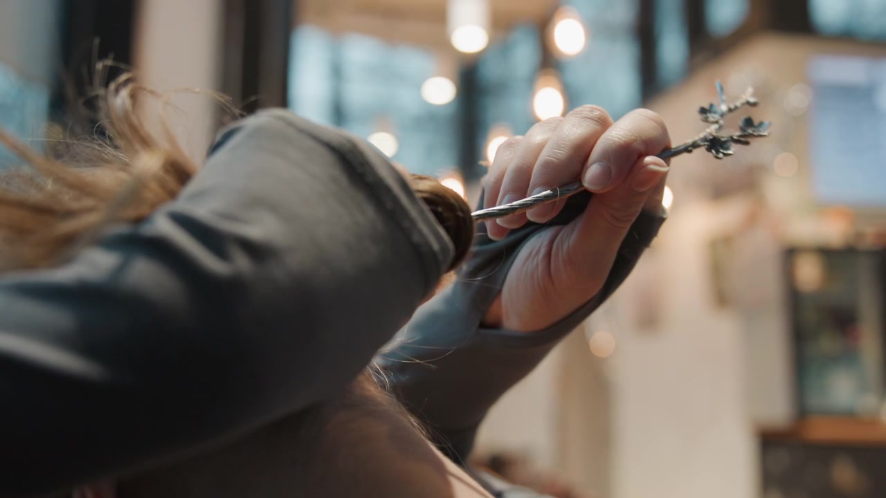 Woman arranging hair. Woman styling her hair behind cafe scene. Intimate moment as woman prepares for her work shift. Quiet behind scenes as woman arranges hair in cozy cafe environment