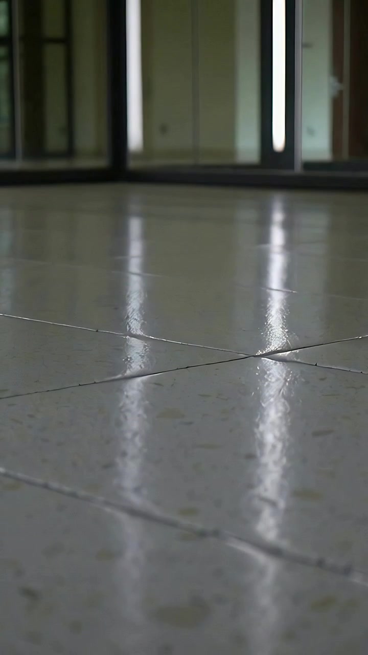 Video vertical: Cámara que retrocede mostrando un rayo de luz en el suelo de baldosas junto al cristal para mostrar una habitación vacía