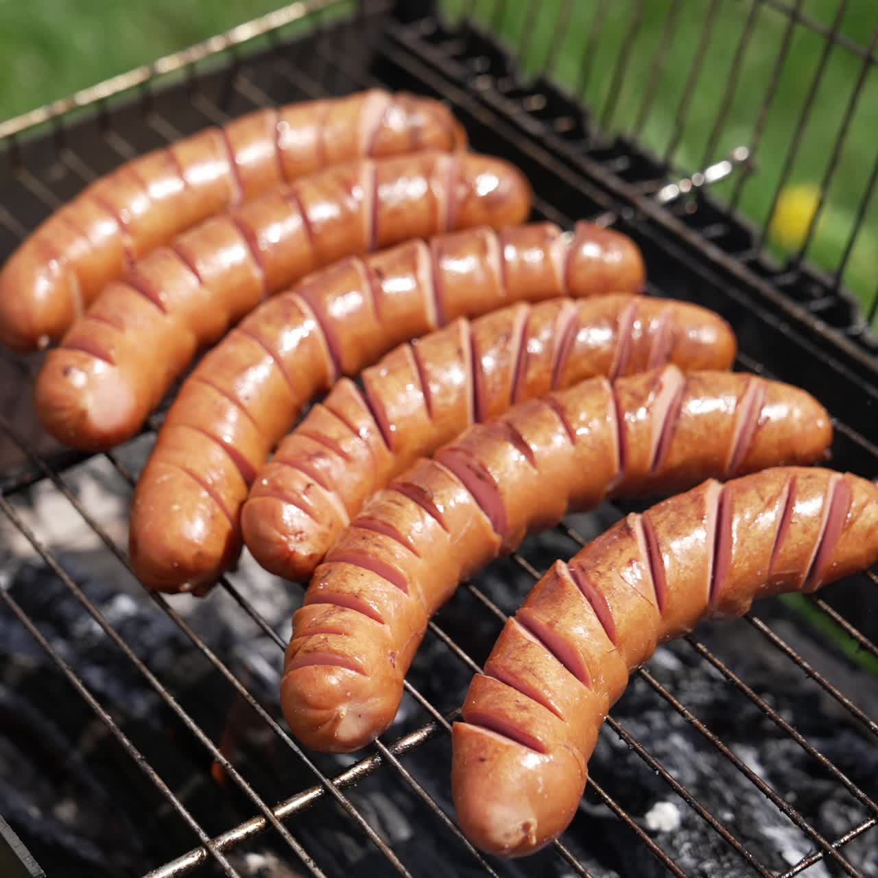 Juicy sausages frying on a fire. Sausages grilling on the barbecue. Hot delicious meat