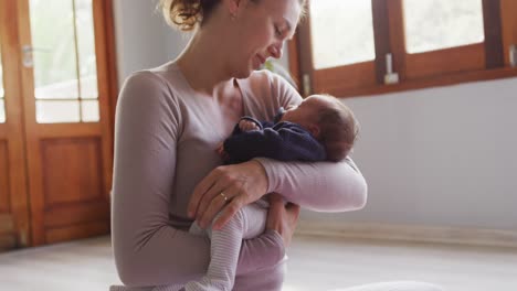 video of caucasian mother and newborn baby on yoga mat