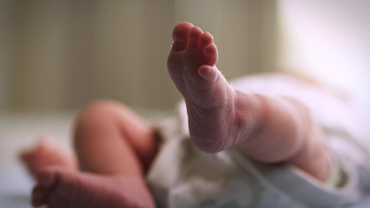Close up of tiny newborn baby feet resting peacefully on a soft cozy blanket in the nursery
