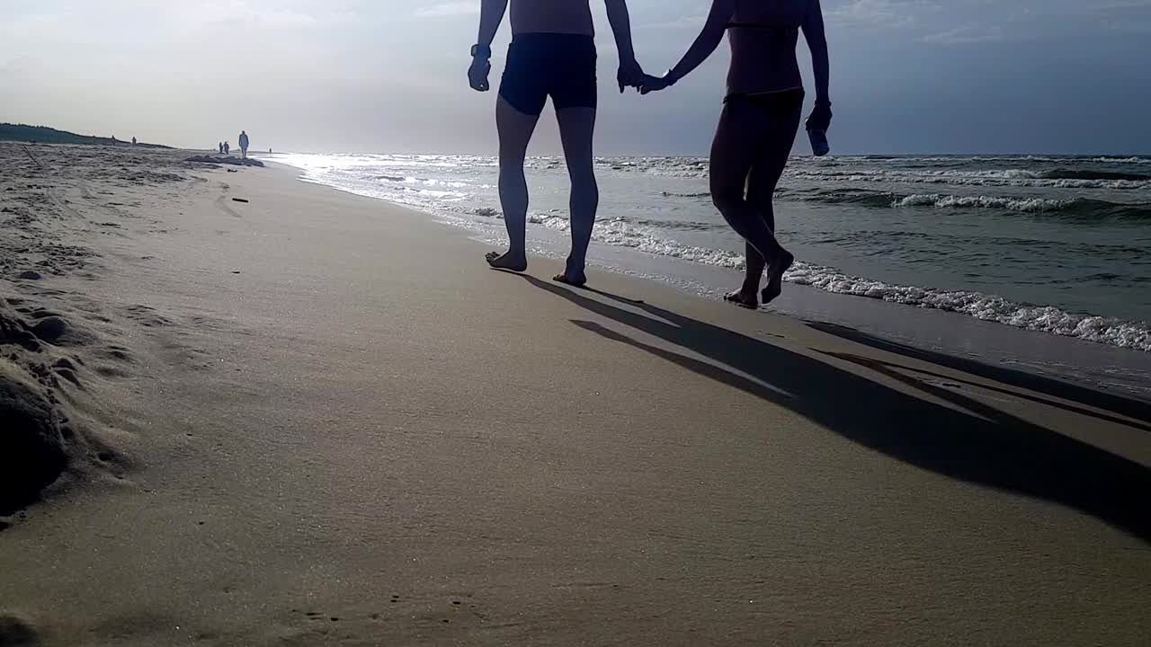 손을 잡고 모래사장을 걷는 남자와 여자