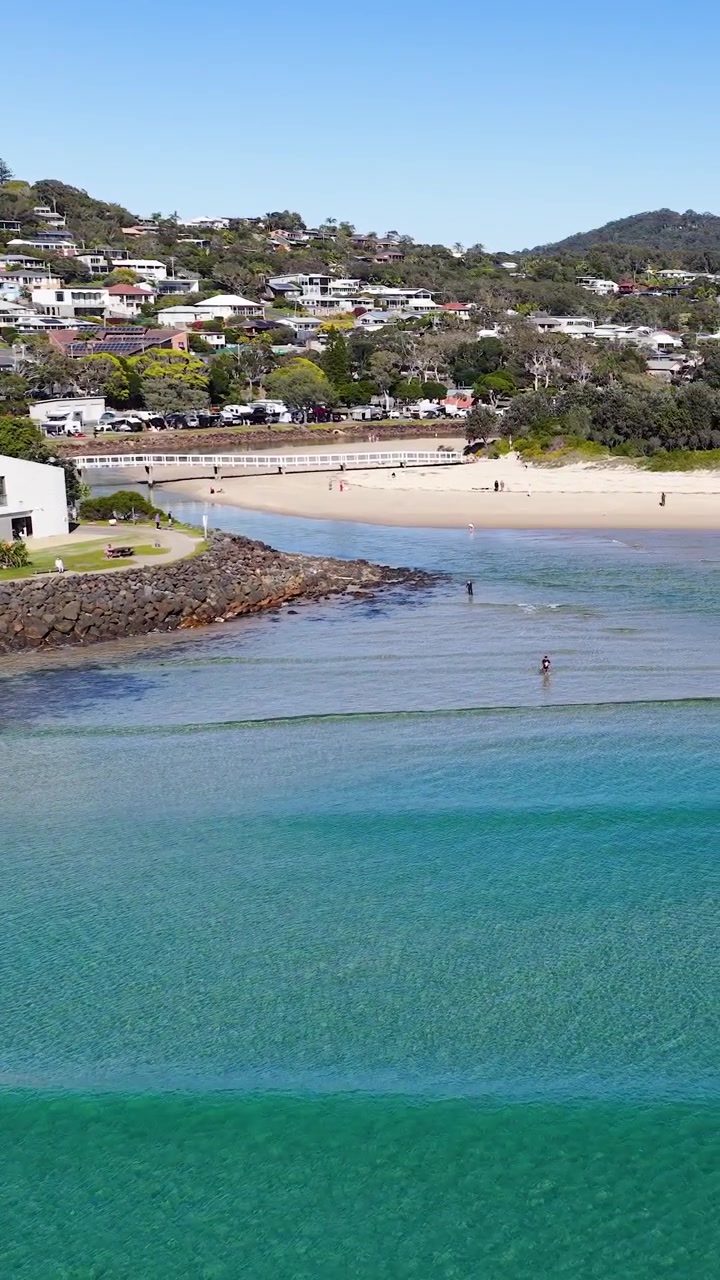 Høyt vinkelbilde av klare turkise havbølger som ruller mot en sandstrand i Australia.