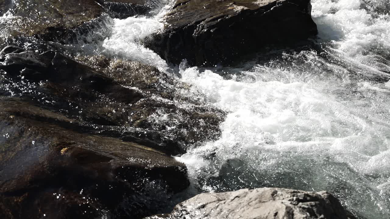 River flowing swiftly over rugged rocks in a serene natural setting. Slow Motion