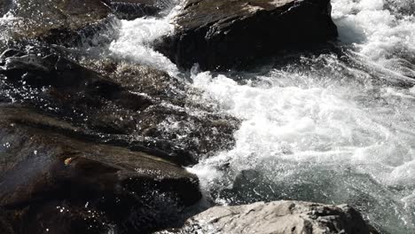 river flowing swiftly over rugged rocks in a serene natural setting. slow motion