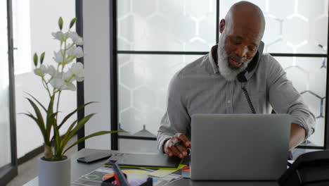 Man-talking-on-landline-while-using-laptop-on-desk-4k