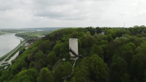 Drones-Aéreos-Vuelan-área-Verde-Boscosa,-Edificio-De-La-Torre-Del-Castillo-Blanco-En-Polonia-árboles-Alrededor-Del-área-De-La-Bahía-Del-Río-Vístula,-Ciudad-De-Kazimierz-Dolny