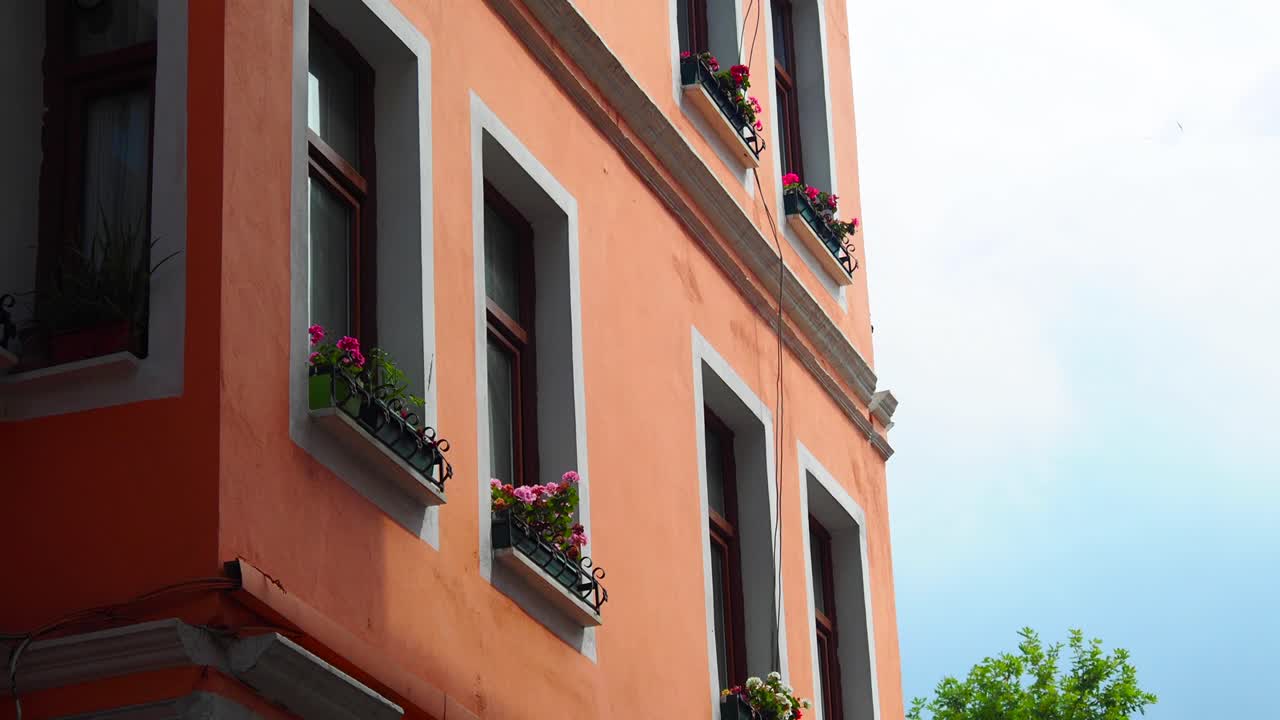 closeup de un antiguo edificio naranja con flores rosas en cajas de ventana