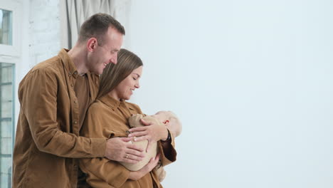 charming caucasian parents looking at their sleeping child with love. happy parents with infant stand at the window.