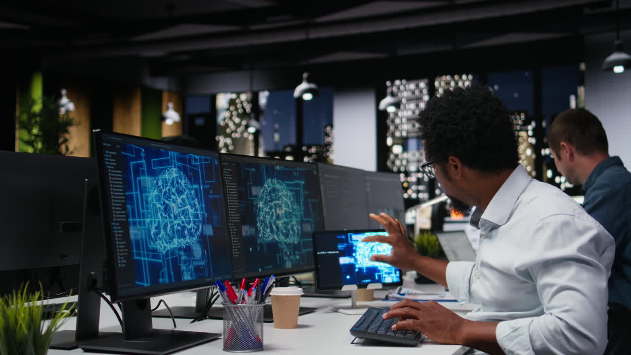 African American Programmer Working on Multiple Screens in Modern Office