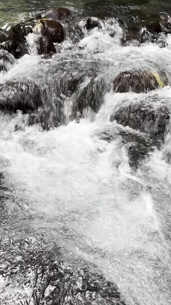 Primo piano dinamico di acqua di fiume impetuosa e rocce