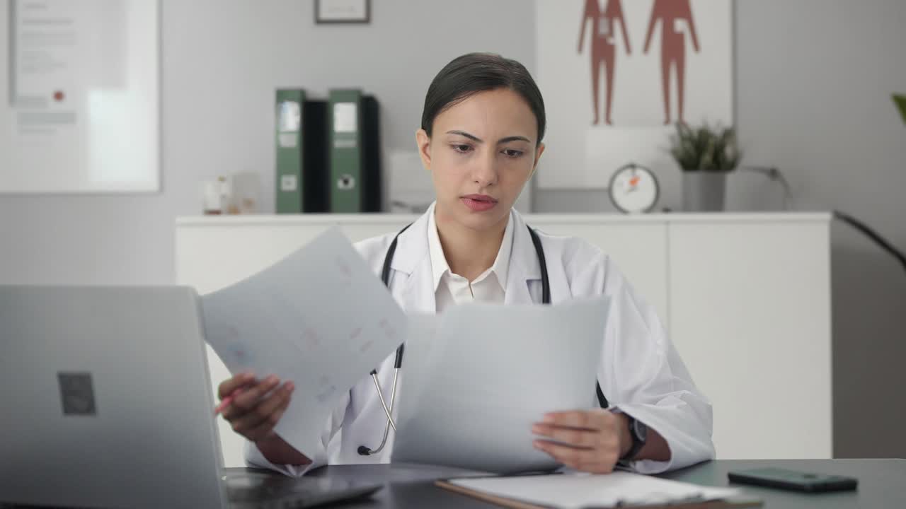 Premium stock video - Indian female doctor checking medical reports