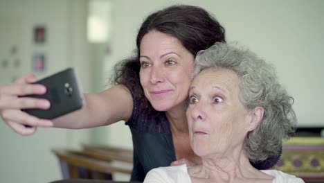 hija y madre haciendo selfie en el teléfono, haciendo caras