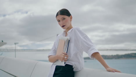 businesswoman posing street documents cloudy day. girl holding papers vertical.