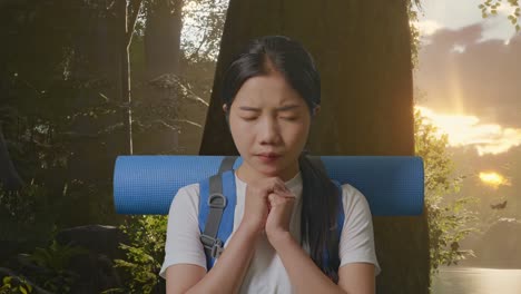 산악 배을 들고 있는 아시아 여성 하이커가 숲의 자연을 탐험하는 동안 무언가를 위해 기도합니다.