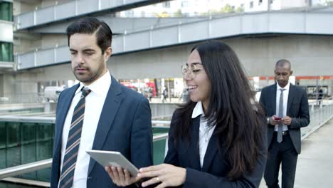 young business colleagues using tablet pc on street