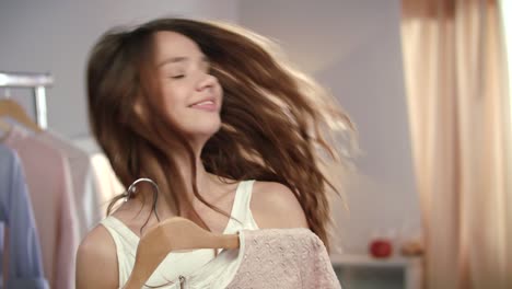 young woman choosing clothes at wardrobe. joyful woman trying on new clothes