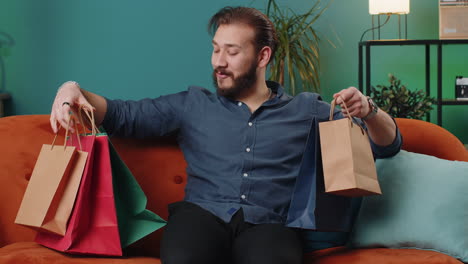 happy man on a couch holding shopping bags