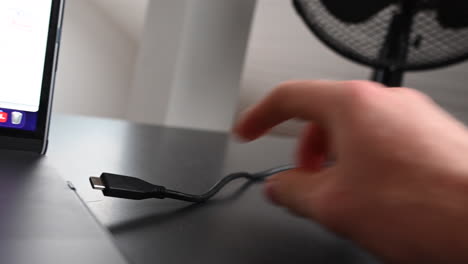 an electronice device user unplugs an external hardrive from the side of his laptop