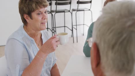 senior male and female friends sitting at a table together socialising before their ballroom dancing