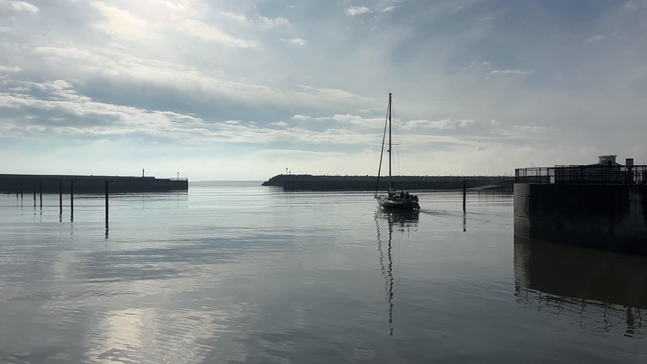 Segelbåt lämnar Hartlepool Marina i nordöstra England, Storbritannien vid soluppgång tidigt på morgonen, kustscen