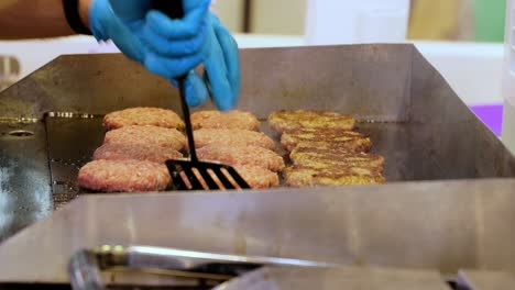 Meat-beef-patty-is-cooked-in-a-hot-frying-pan.-Street-food,-chef-flips-burgers-with-a-spatula.