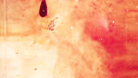 oil and red food coloring being poured into water