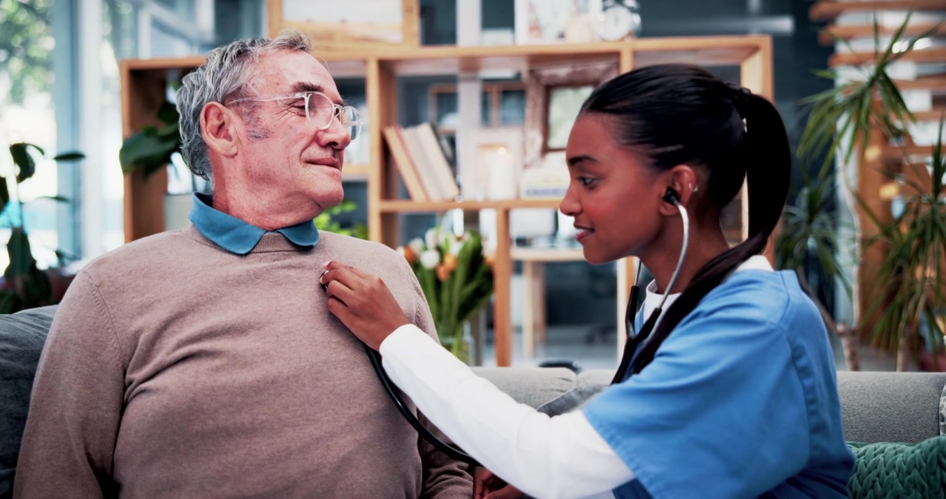Young Nurse Examining Senior Man With Stethoscope at Home