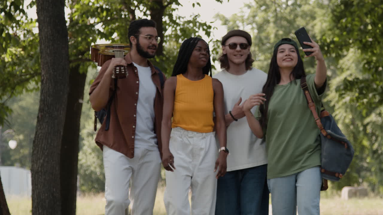 Group of diverse friends walking in a park, taking a selfie and enjoying their time