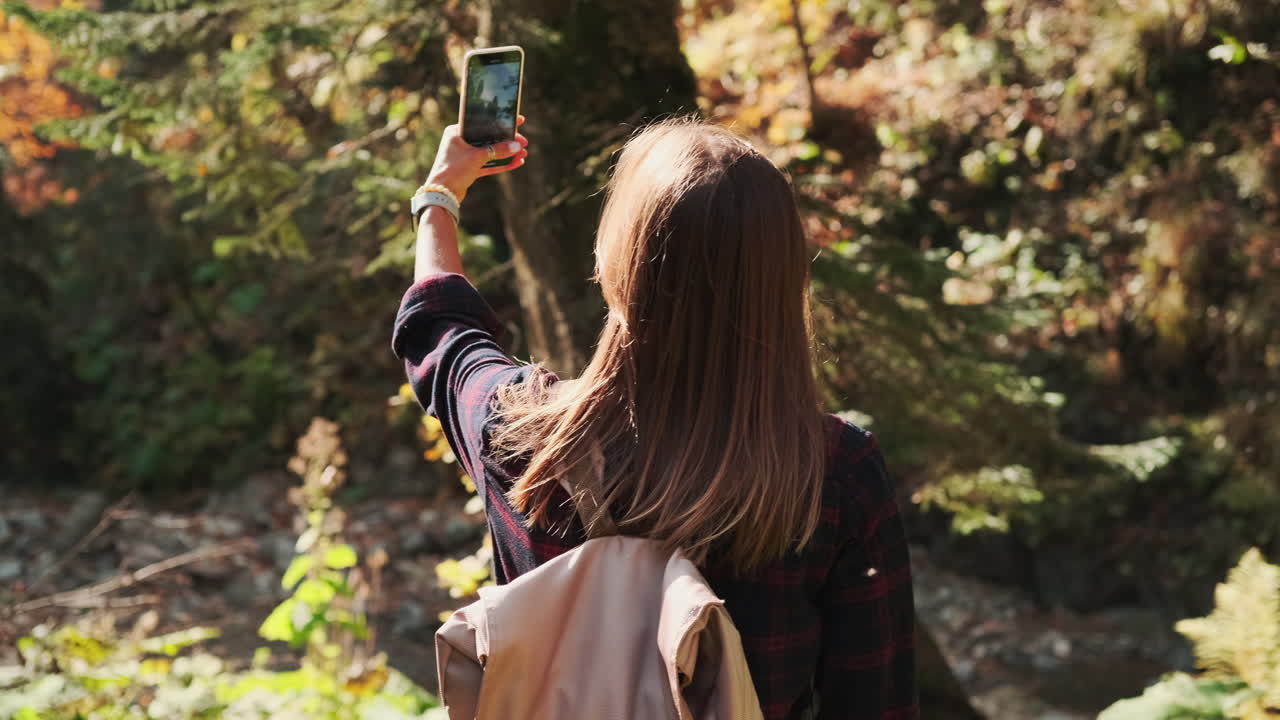 mujer tomando una selfie en un bosque durante el otoño
