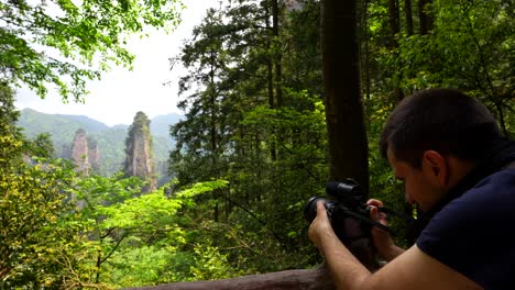 turista capturando los famosos pilares de piedra arenisca de zhangjiajie en un bosque verde exuberante, china