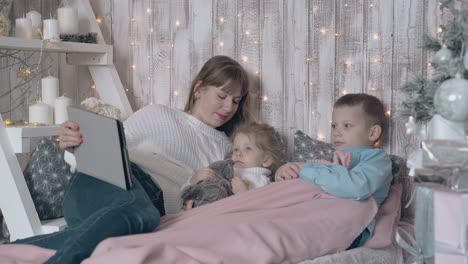 family watches cartoons on tablet on comfortable bed