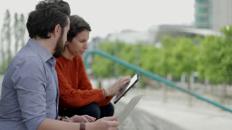 couple using digital devices on street