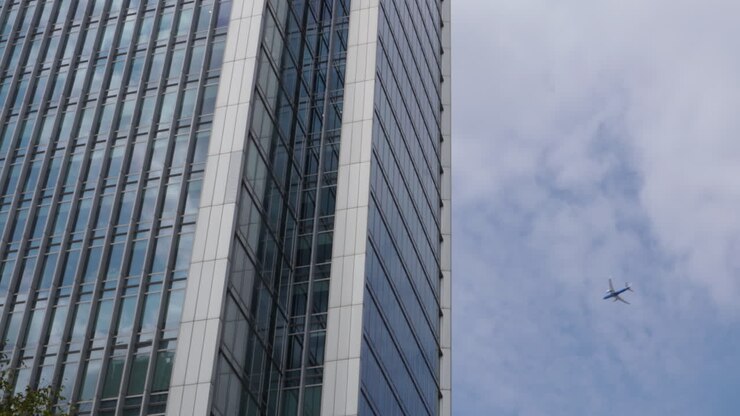 Un aeroplano commerciale vola dietro un grattacielo aziendale a Canary Wharf, Londra, Regno Unito