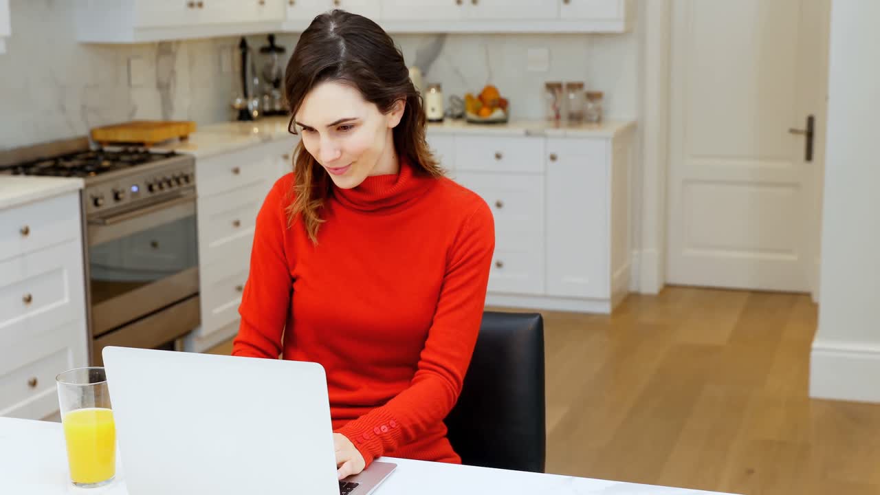 mujer usando portátil en la cocina 4k