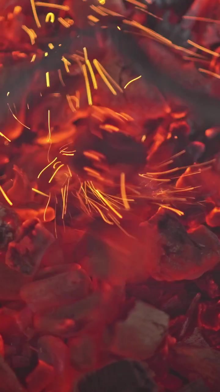Close-up de brasas de carvão vermelhas incandescentes com faíscas voando