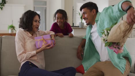 happy hispanic woman getting presents from huband and daughter