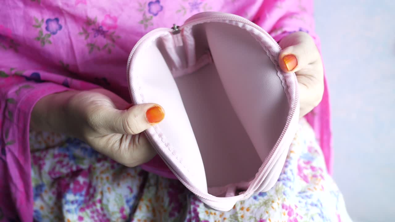 Donna che tiene una trousse per il trucco rosa vuota