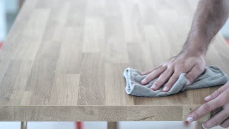 efficient cleaning: man wiping wooden table with cloth