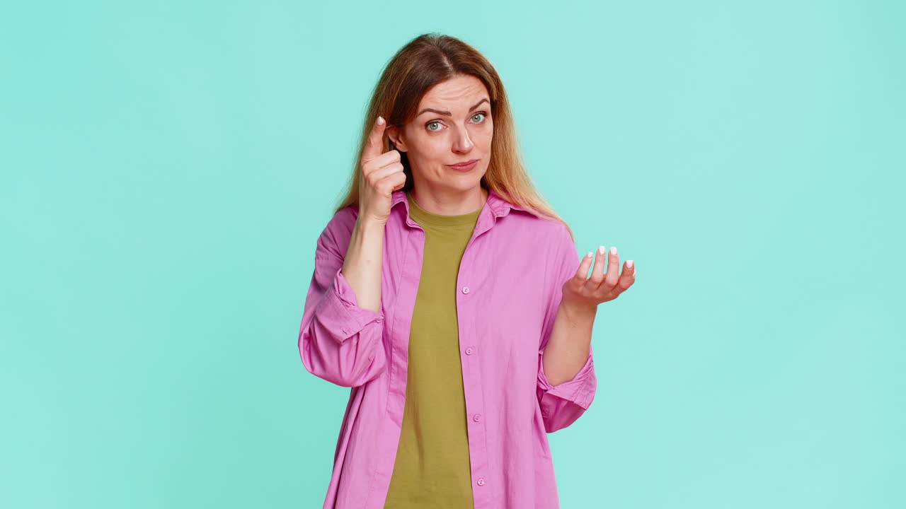 Woman spinning finger near temple showing crazy gesture disbelief or joking insult to silly behavior