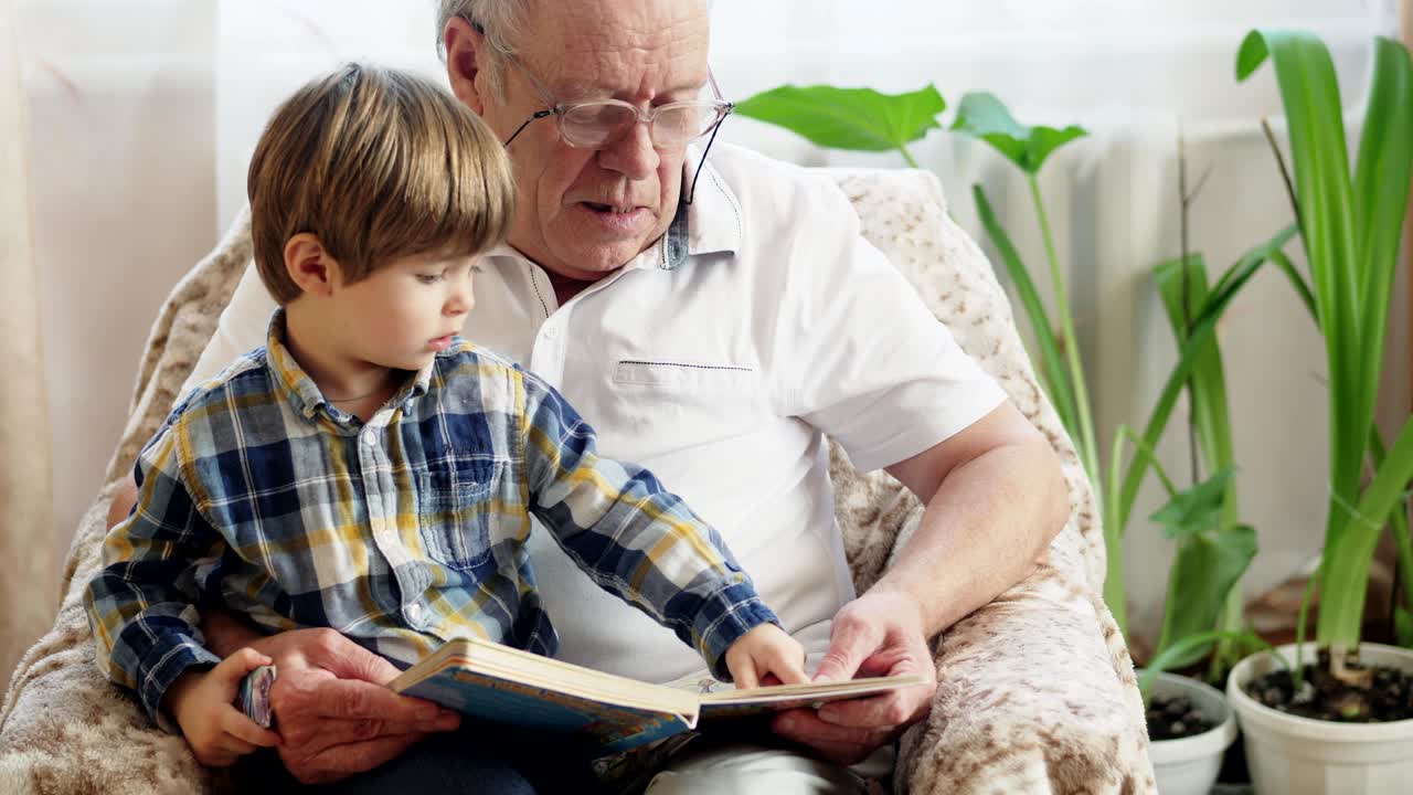 un niño pequeño leyendo un libro con su abuelo.